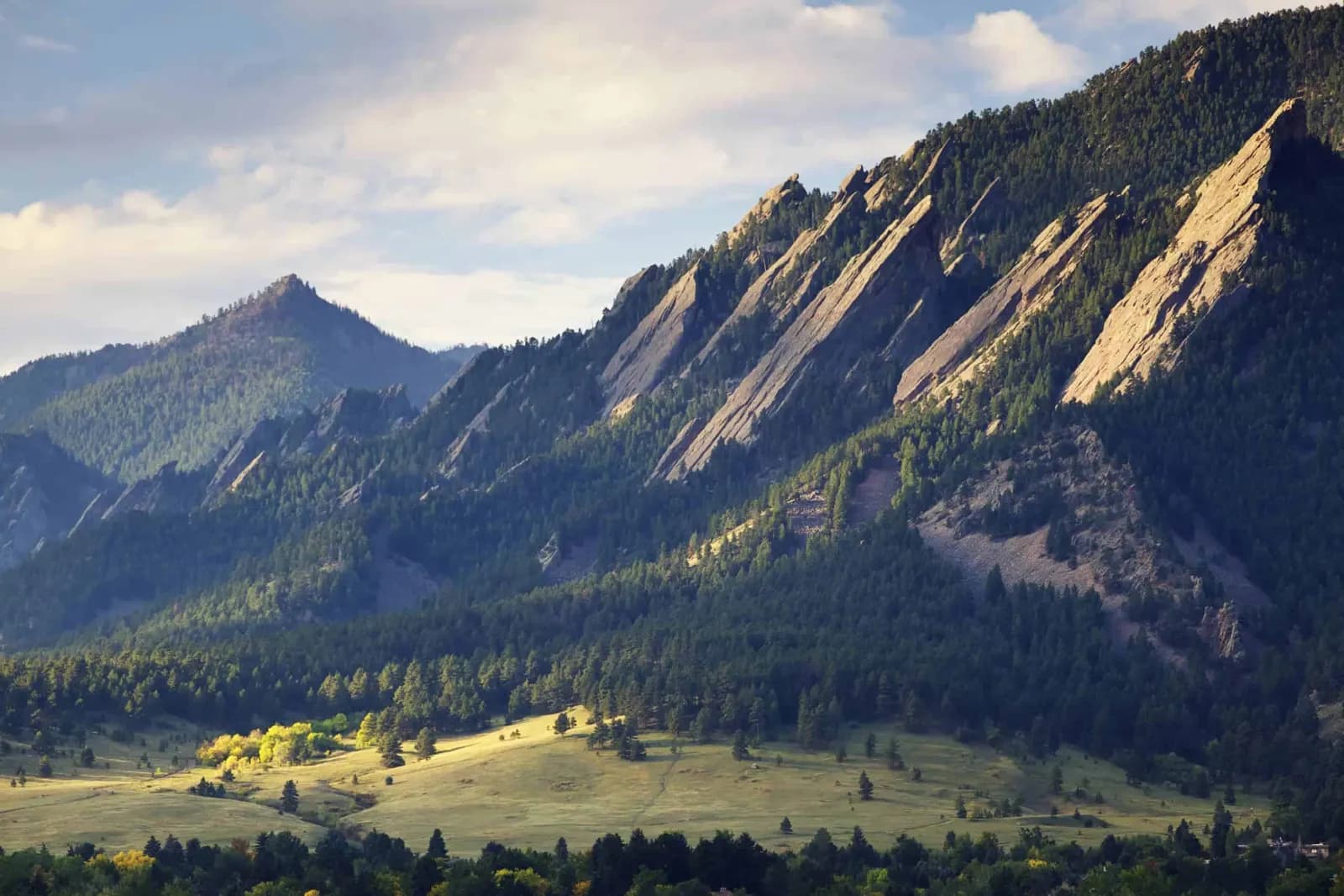 Morning light on the Flatirons above a green meadow